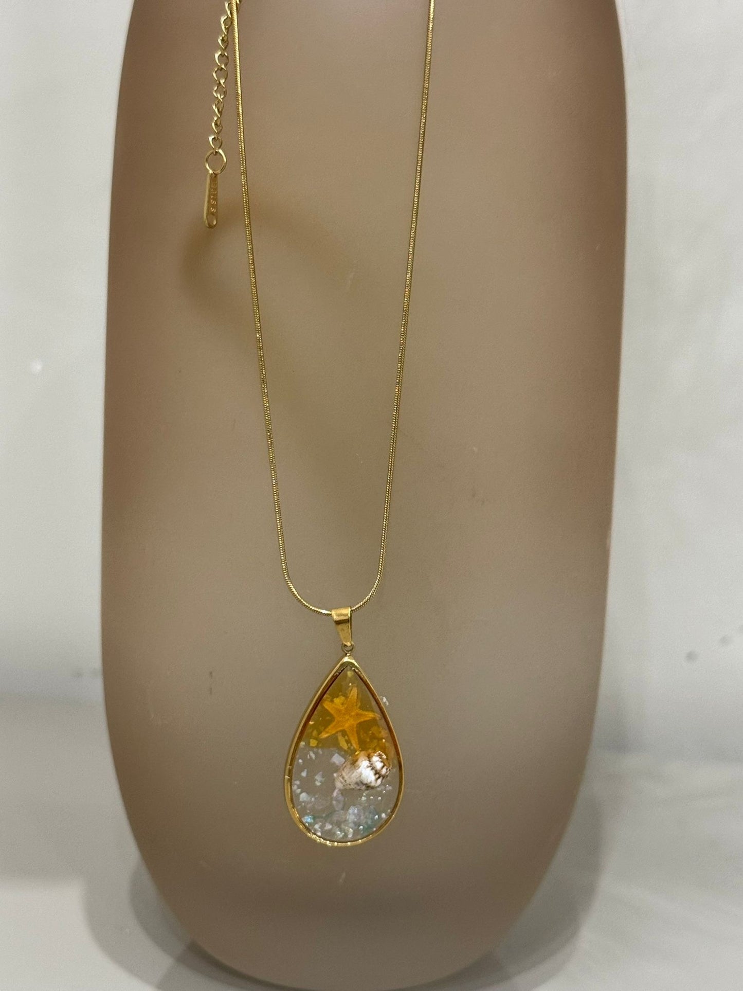 Collana Sharm base oro con ciondolo a goccia contenente una stella marina e una conchiglia incapsulata