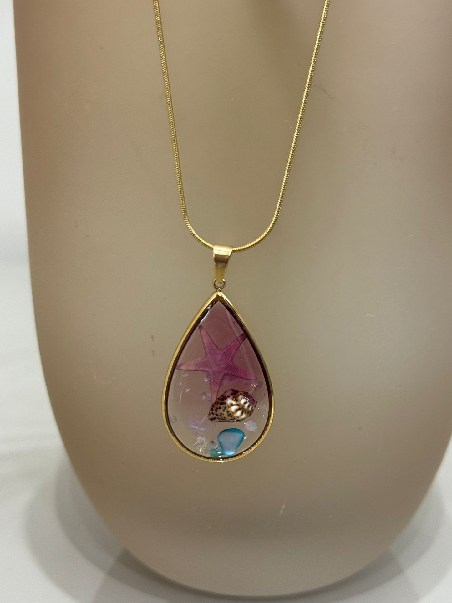Collana Sharm base oro con ciondolo a goccia contenente una stella marina e una conchiglia incapsulata