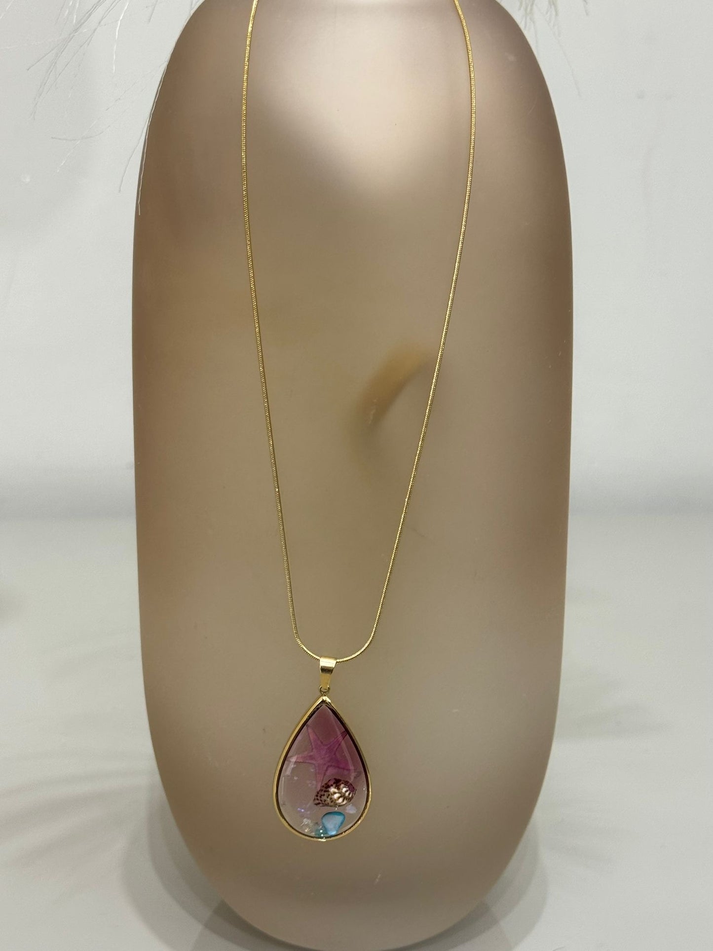 Collana Sharm base oro con ciondolo a goccia contenente una stella marina e una conchiglia incapsulata